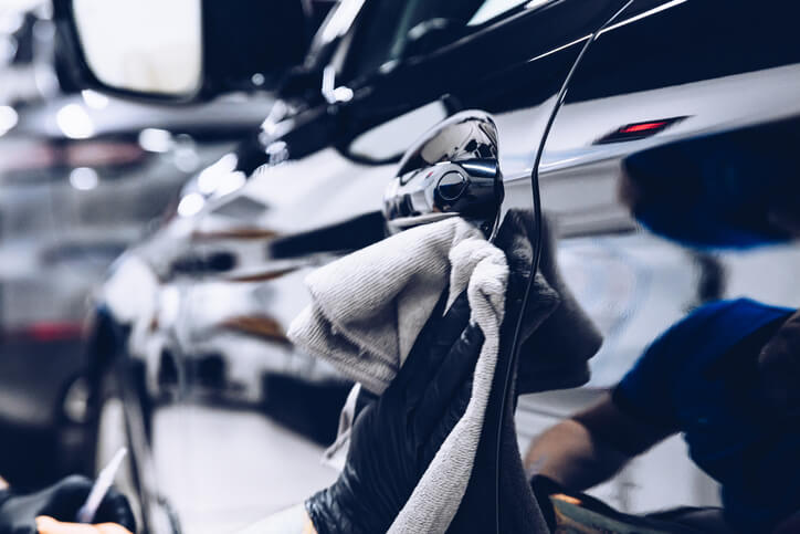 hand drying a car with a towel after a wash